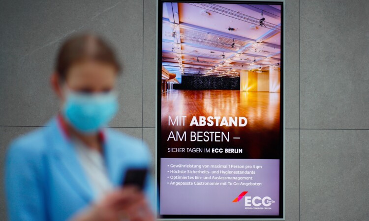 Maksed staff with screen with hygiene measures at the ECC Berlin