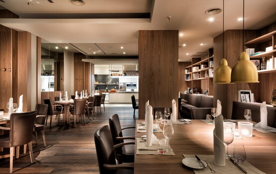 Eingedeckte Tische in Wohnzimmer-Atmosphäre und Showküche